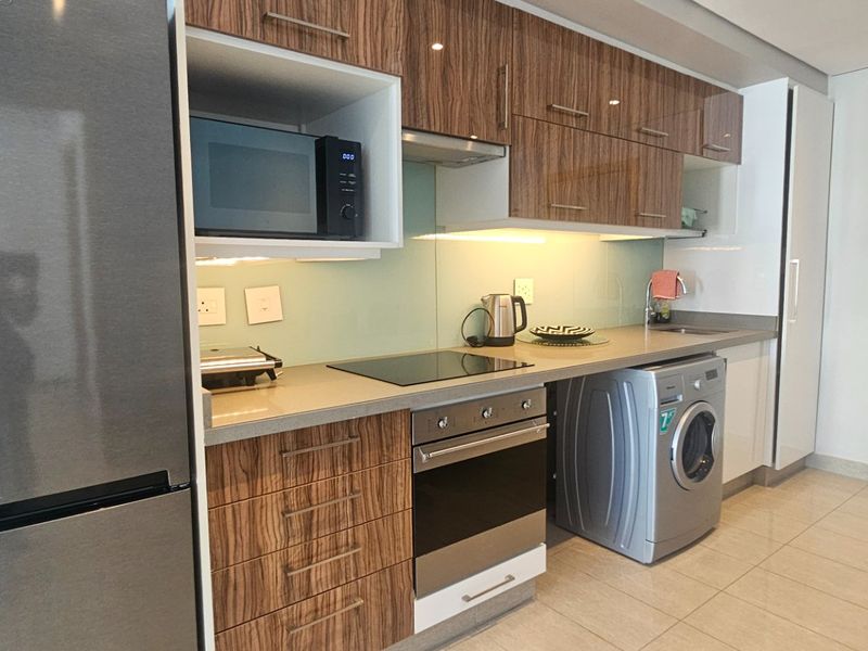 Modern kitchen featuring wood-grain cabinetry, stone countertops, glass splashback, integrated appliances, and tiled flooring.
