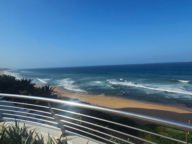 A stunning panoramic ocean view captured from a balcony featuring a modern stainless steel balustrade overlooking the coastline.
