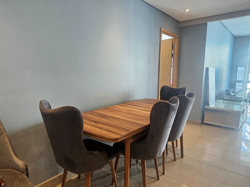 Open plan living and dining area featuring tiled flooring, recessed lighting, and access to a balcony through large glass sliding doors.