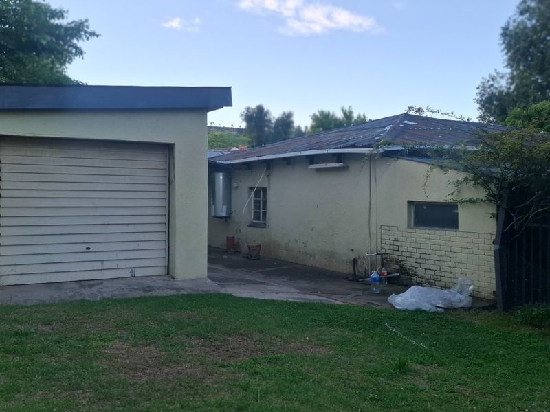 Rear view of the property featuring a detached garage with a roller shutter door and a paved backyard area.