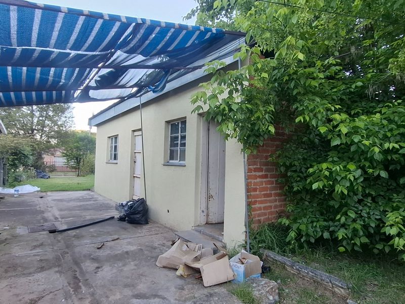 Rear exterior view of the property featuring a concrete patio area, external geyser, and a damaged shade cloth awning structure.