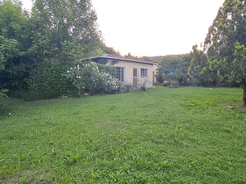 A spacious rear garden featuring a large lawn area and mature trees, providing a private outdoor space behind the main dwelling.