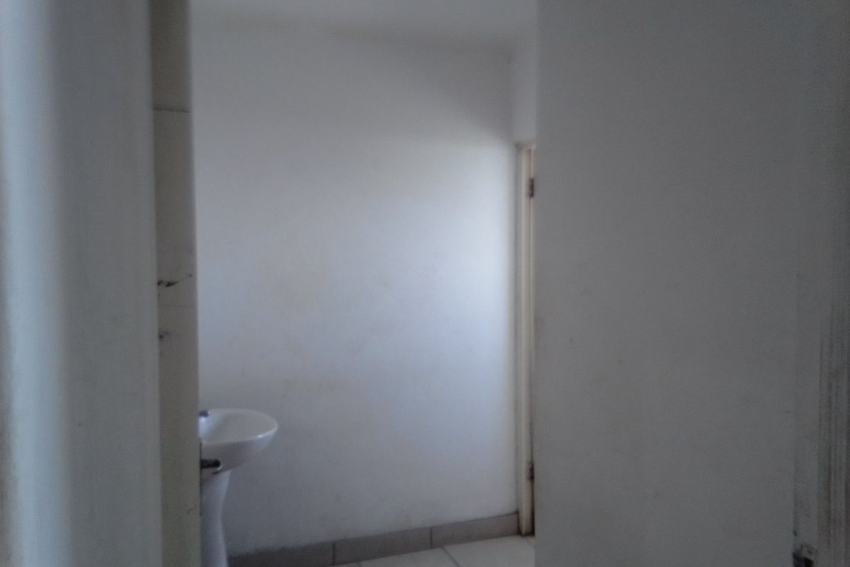 A small, empty bathroom featuring a pedestal basin and tiled flooring, requiring cosmetic updates to improve its overall condition.