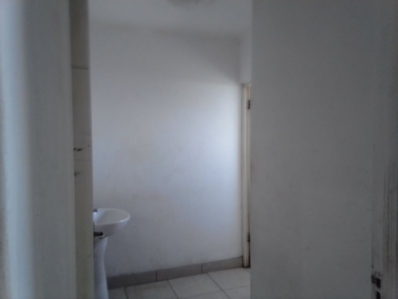 A small, empty bathroom featuring a pedestal basin and tiled flooring, requiring cosmetic updates to improve its overall condition.