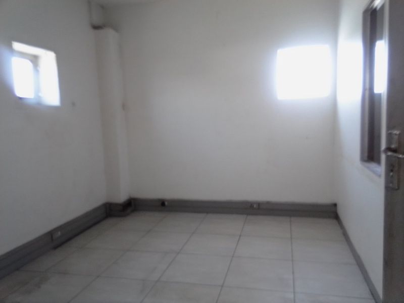 An empty, basic office space featuring tiled flooring and neutral walls, suitable for a variety of commercial uses.