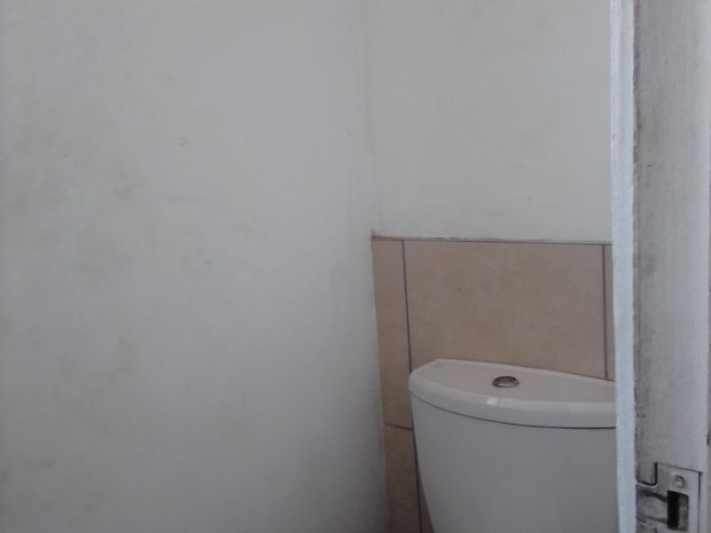 A small, functional bathroom space featuring a standard toilet and tiled splashback, currently requiring cosmetic updates to the wall finishes.