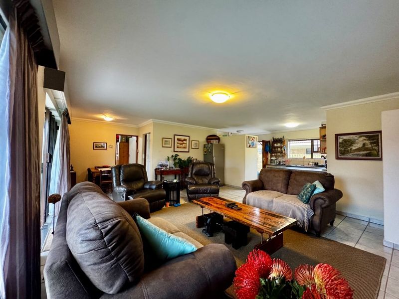 Spacious open-plan living area featuring tiled flooring, neutral walls, and direct access to the outdoors through sliding glass doors.