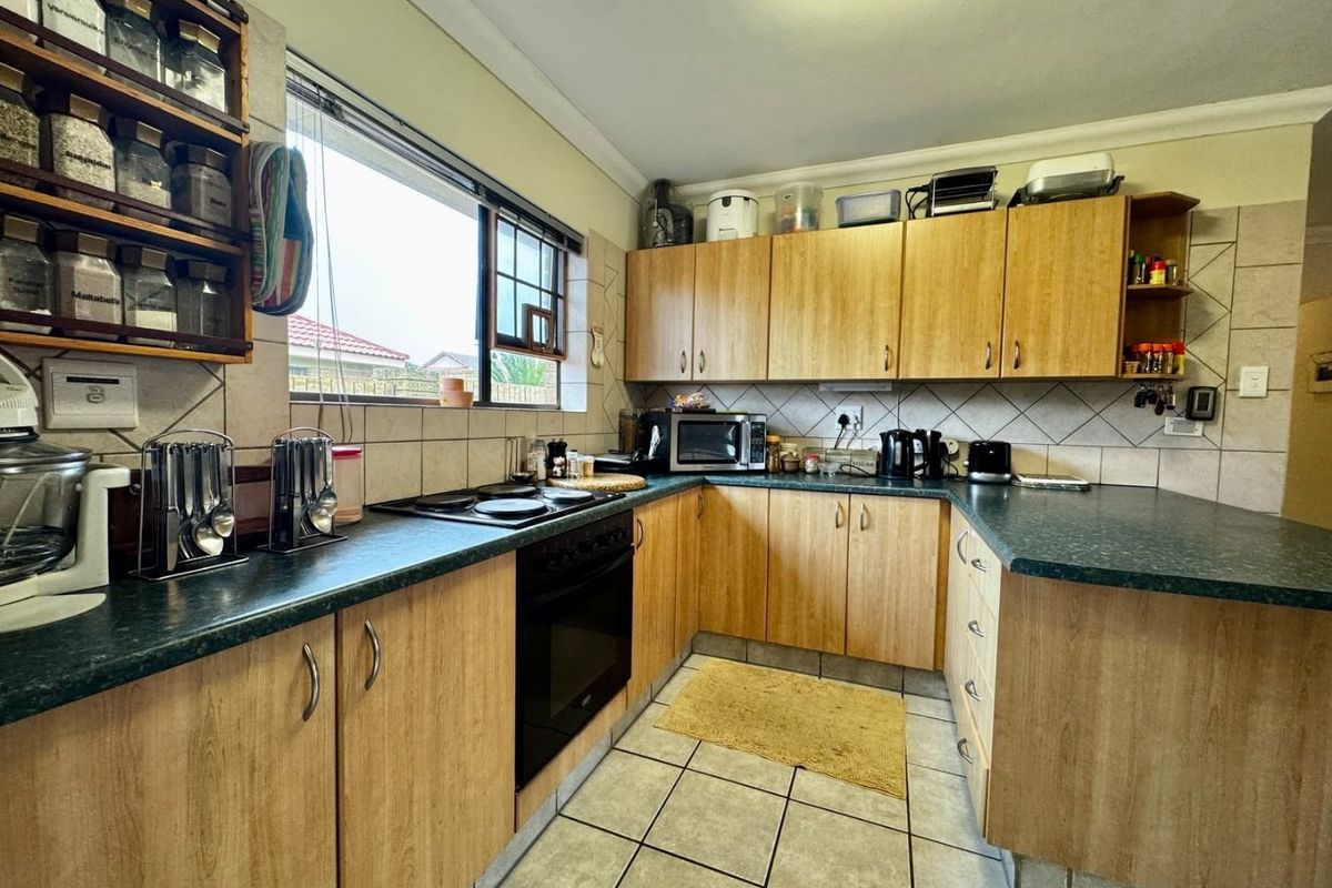 A functional kitchen featuring wood-look laminate cabinetry, dark countertops, a built-in oven, and a tiled backsplash, offering a practical layout for daily meal preparation.