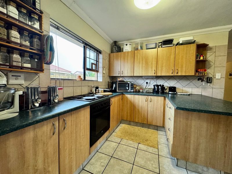 A functional kitchen featuring wood-look laminate cabinetry, dark countertops, a built-in oven, and a tiled backsplash, offering a practical layout for daily meal preparation.