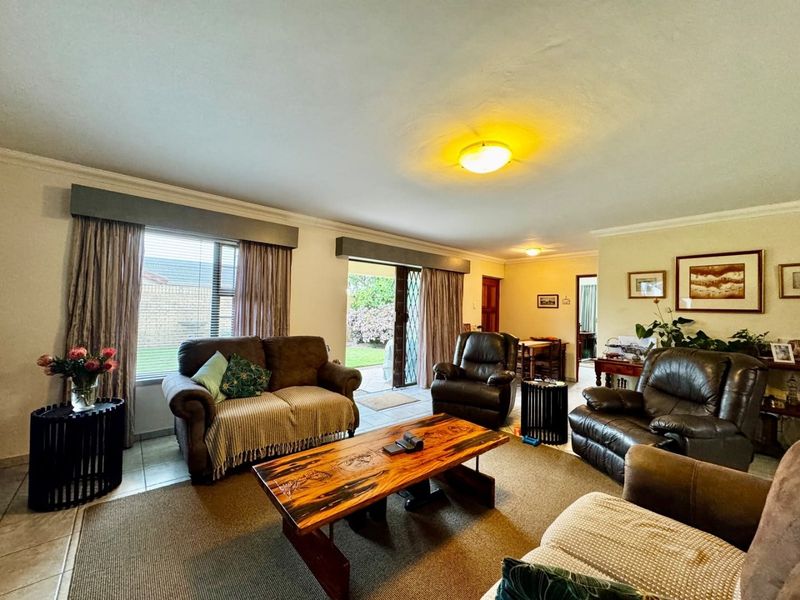 Spacious living room featuring tiled flooring, large windows, and a sliding glass door providing direct access to the outdoor patio area.
