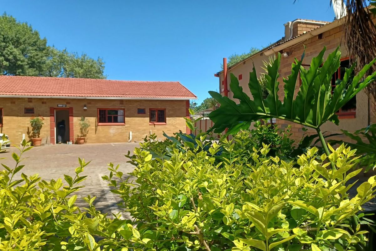 A view of the paved courtyard area between commercial face brick buildings with tiled roofs, featuring established garden landscaping.