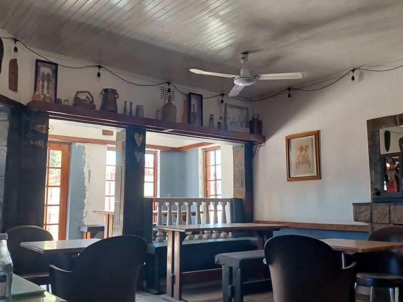 Open plan commercial space featuring a stone fireplace, timber-clad ceiling, and decorative balustrade, offering a rustic atmosphere with potential for interior updates.