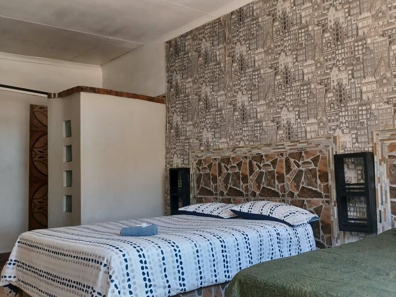 Bedroom featuring a unique stone-tiled headboard, decorative wallpaper, and a partition wall with glass block accents.