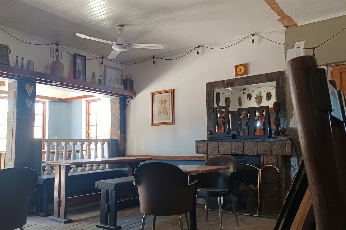 A rustic commercial interior featuring a stone fireplace, timber ceiling, and traditional balustrade, currently showing signs of wear and requiring cosmetic updates.