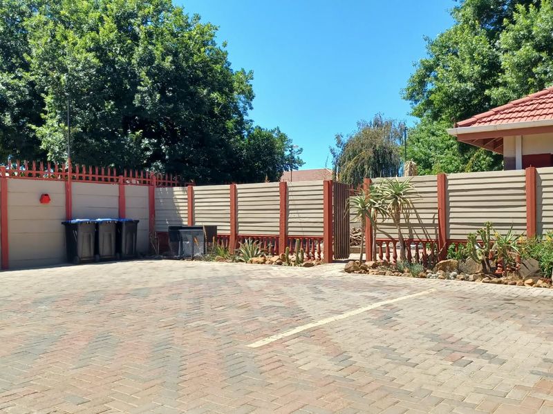 A paved rear courtyard area featuring a secure precast concrete boundary wall with integrated security spikes and a pedestrian access gate.