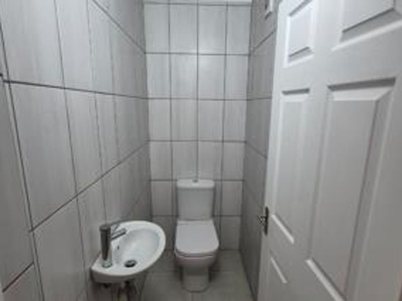 A compact, tiled guest bathroom featuring a modern toilet and a wall-mounted basin.