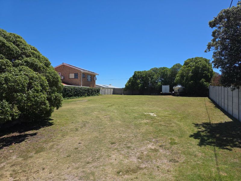 A spacious, level residential plot featuring a well-maintained lawn and secure precast concrete boundary walls, offering a clear space for future development.