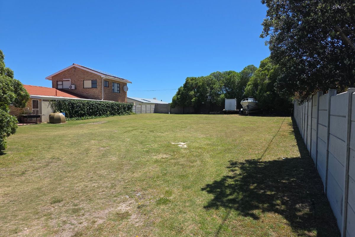 A spacious, level residential plot featuring a well-maintained lawn, enclosed by precast concrete boundary walls and mature perimeter trees.