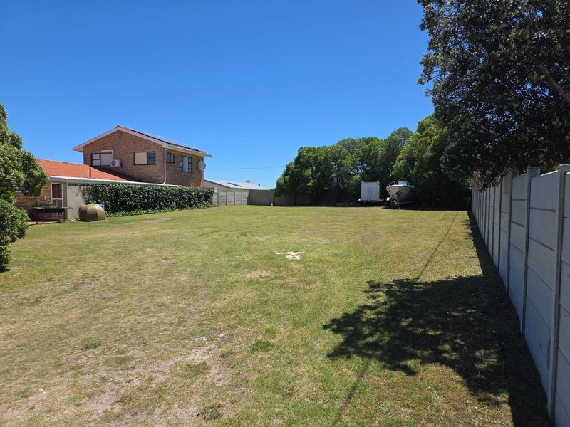 A spacious, level residential plot featuring a well-maintained lawn, enclosed by precast concrete boundary walls and mature perimeter trees.