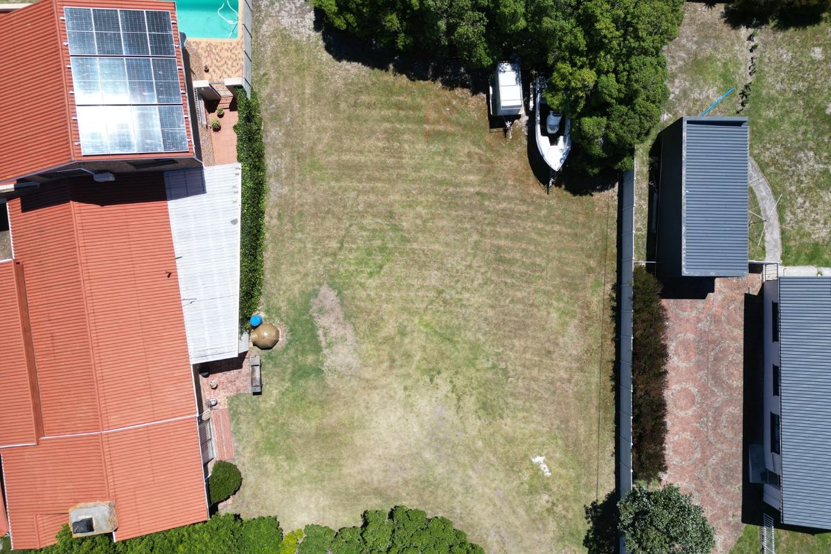 Aerial view of a residential property featuring a large lawn, swimming pool, solar panels, and paved driveway area.
