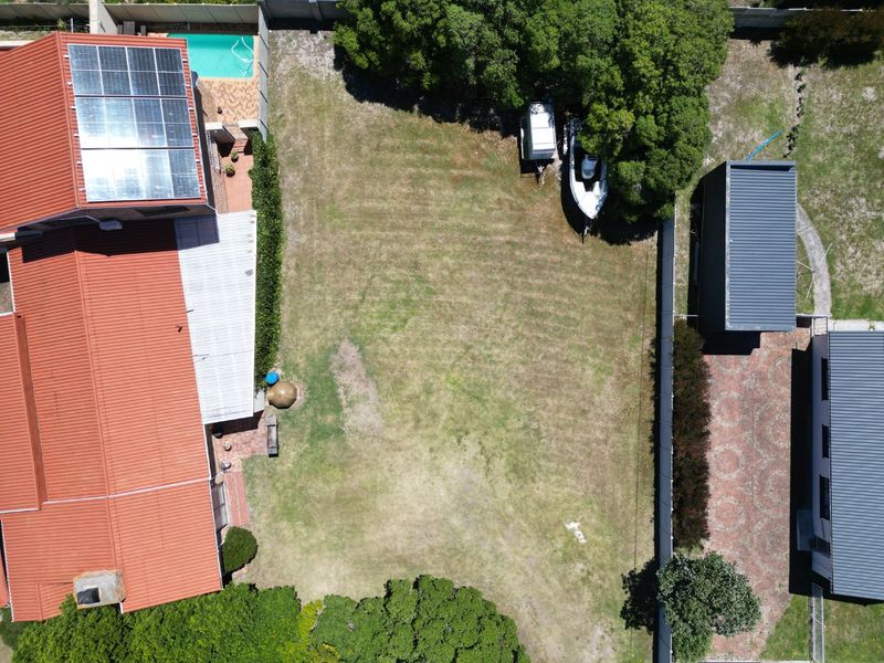 Aerial view of a residential property featuring a large lawn, swimming pool, solar panels, and paved driveway area.