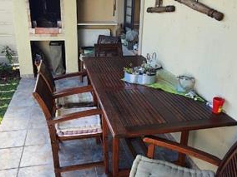 Covered patio area featuring a built-in brick braai and tiled flooring, providing a functional outdoor entertainment space.