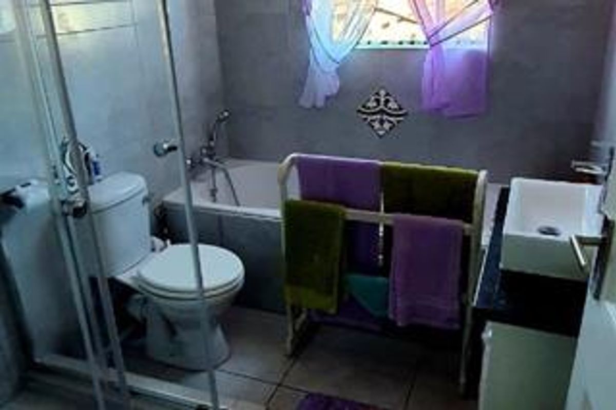 A functional bathroom featuring a bathtub, separate shower enclosure, toilet, and a modern vessel sink set on a vanity cabinet with tiled finishes.