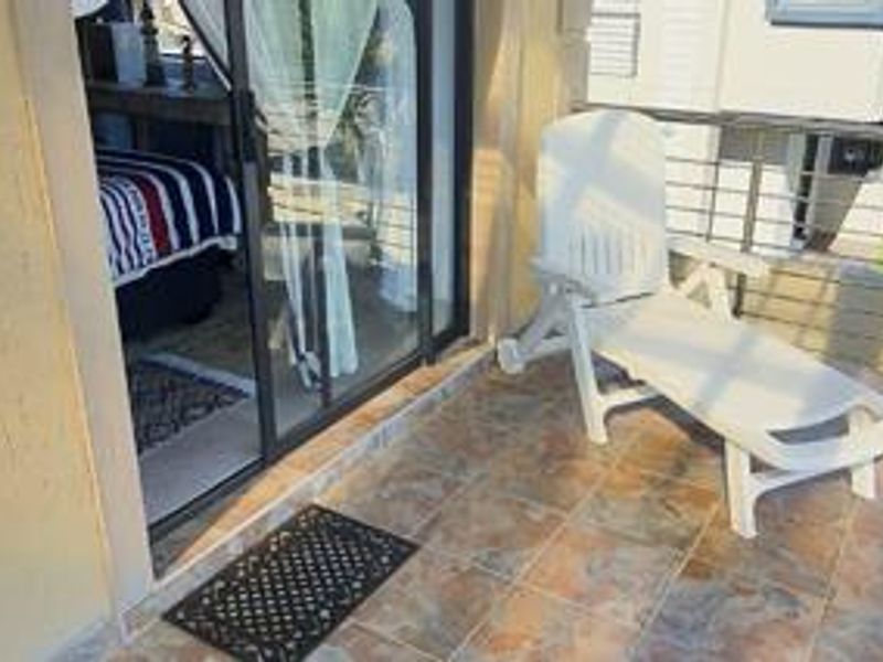 A private balcony featuring tiled flooring, a sliding glass door entrance, and a modern stainless steel cable railing.