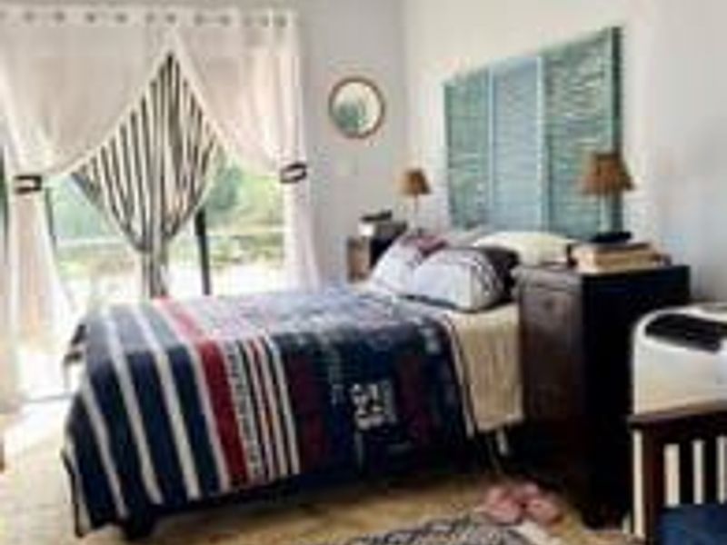 A bedroom featuring tiled flooring and a sliding glass door providing natural light and access to the exterior.