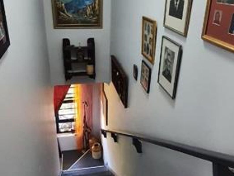 A view looking down a residential staircase featuring a fixed handrail and a window at the landing.