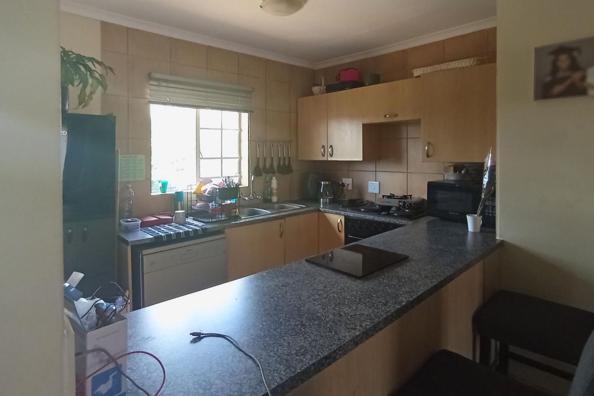 A functional kitchen featuring built-in cabinetry, laminate countertops, a tiled backsplash, and a convenient breakfast bar for casual dining.