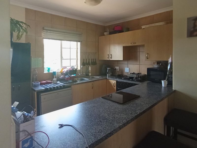 A functional kitchen featuring built-in cabinetry, laminate countertops, a tiled backsplash, and a convenient breakfast bar for casual dining.