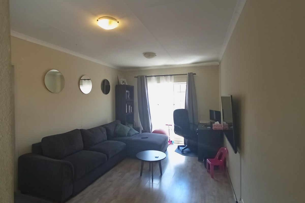 A functional living room featuring laminate flooring and a sliding glass door providing natural light access.