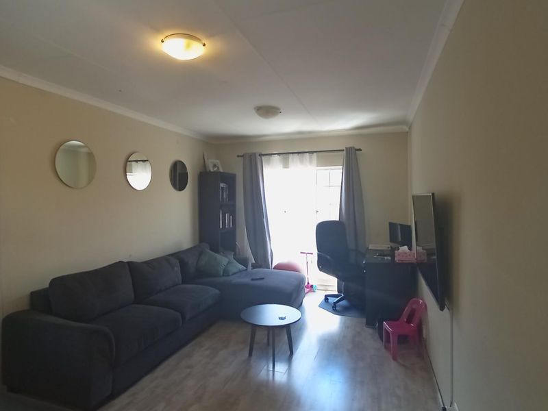 A functional living room featuring laminate flooring and a sliding glass door providing natural light access.