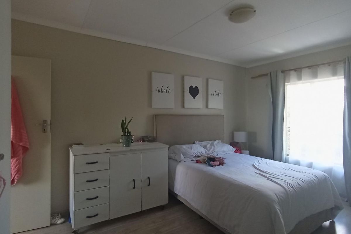 A functional bedroom featuring neutral wall tones, a window with curtains, and a ceiling light fixture.