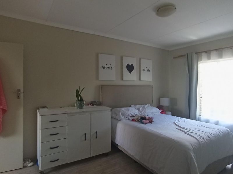 A functional bedroom featuring neutral wall tones, a window with curtains, and a ceiling light fixture.