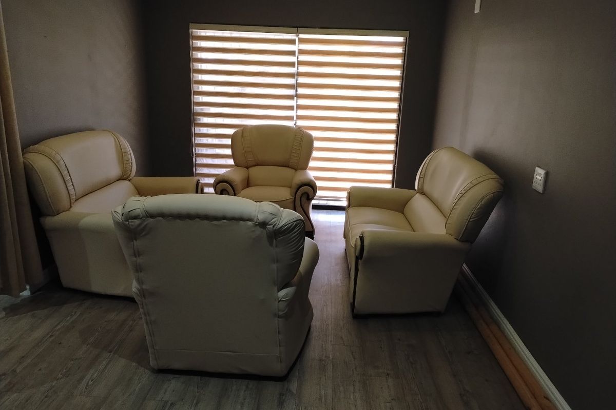 A living room featuring laminate flooring and a large sliding door with roller blinds, providing natural light to the space.