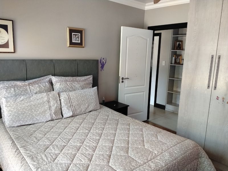 A well-maintained bedroom featuring built-in cupboards, integrated shelving in the adjacent area, and neutral wall finishes.