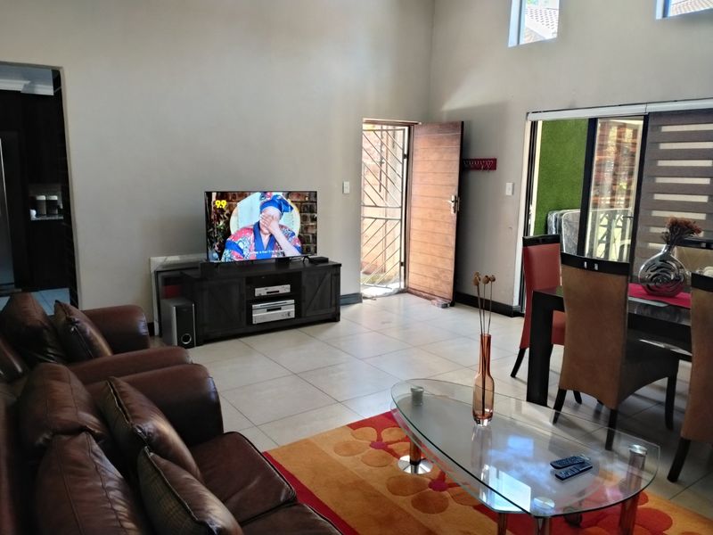 Spacious open-plan living and dining area featuring tiled flooring, high ceilings with clerestory windows, and direct access to an outdoor patio area.