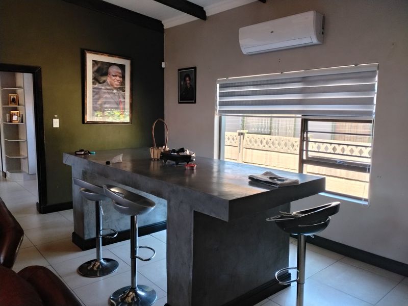 A kitchen area featuring a custom concrete island, tiled flooring, and a wall-mounted air conditioning unit.