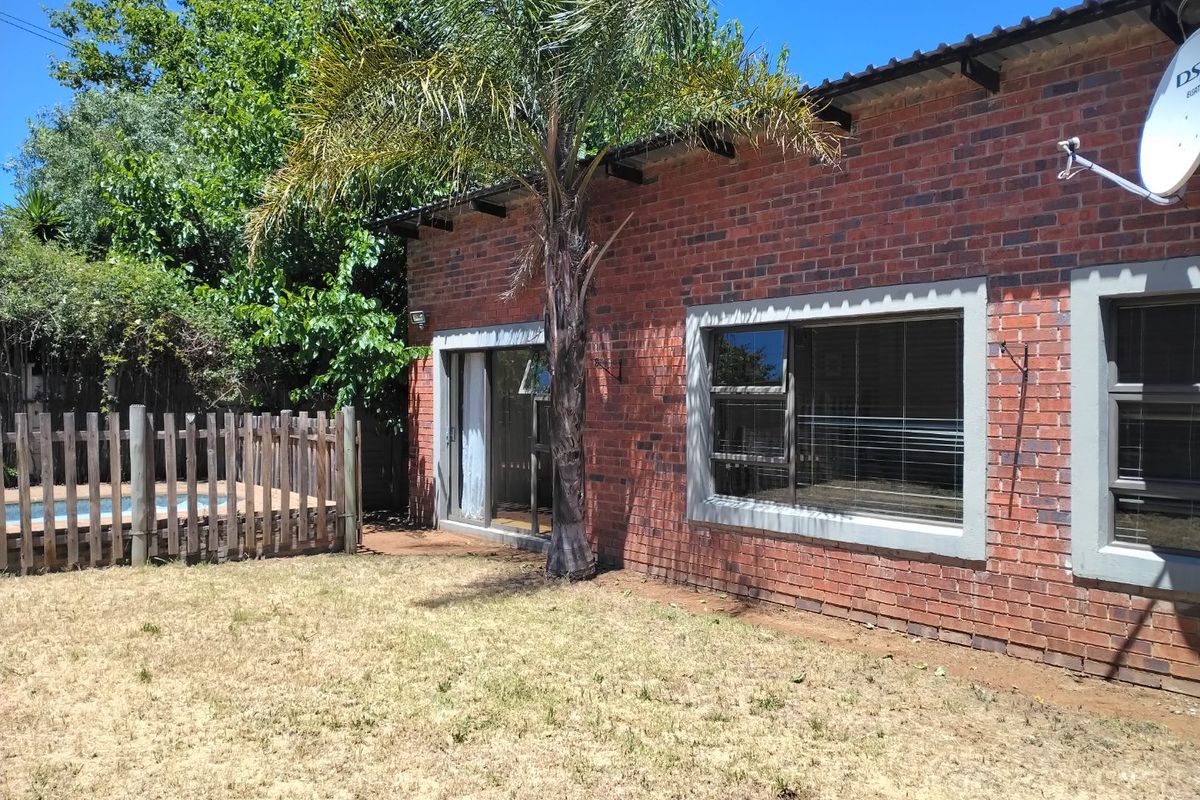 Rear view of the property featuring an exposed brick facade, aluminium windows, a sliding door, and a fenced swimming pool area.