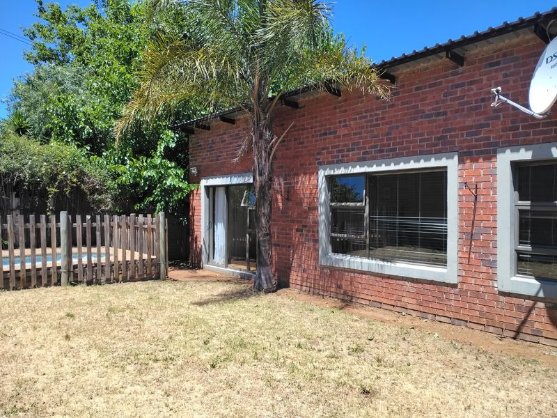 Rear view of the property featuring an exposed brick facade, aluminium windows, a sliding door, and a fenced swimming pool area.