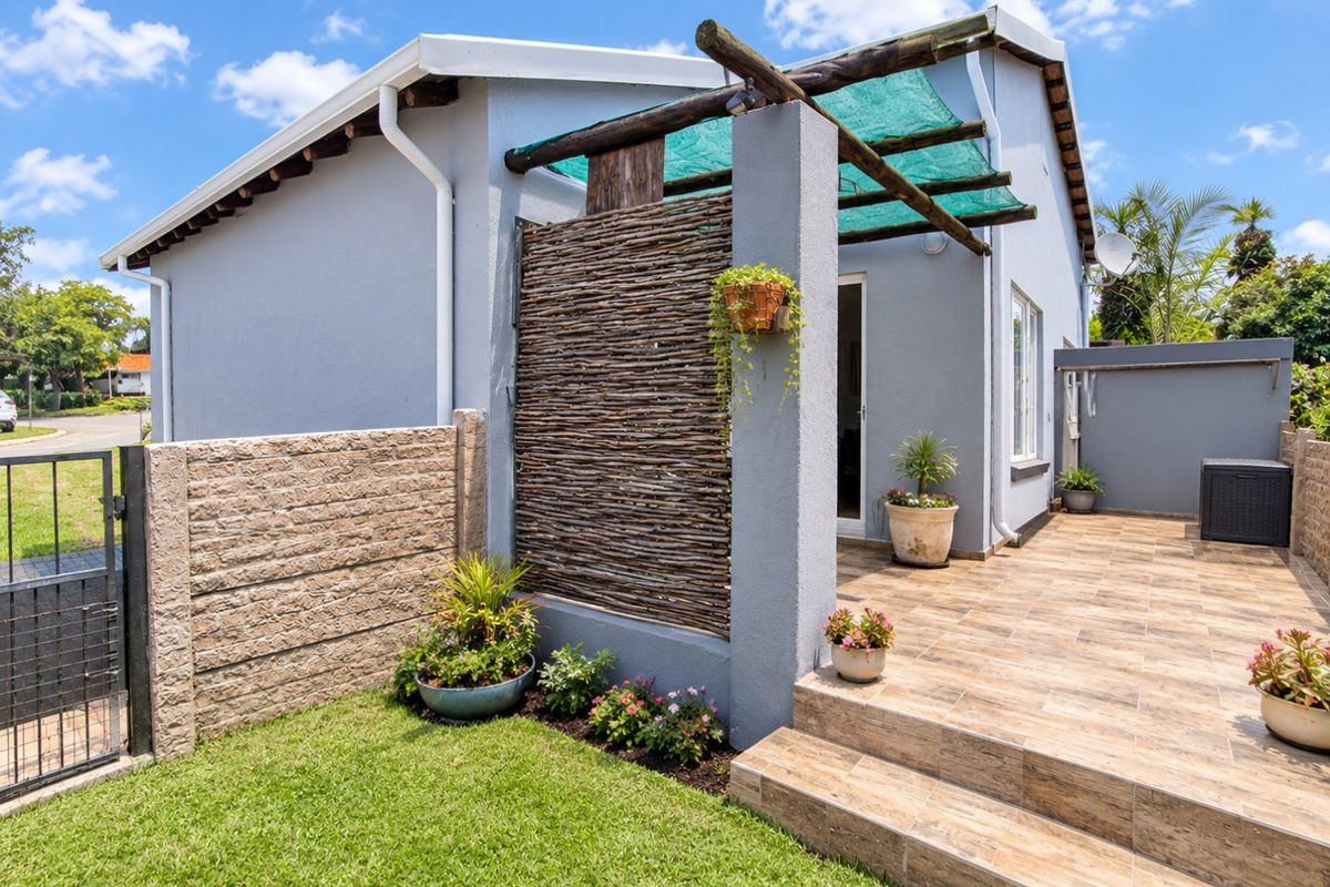 A well-maintained rear townhouse exterior featuring a tiled patio, timber pergola, and private garden area with secure boundary walling.
