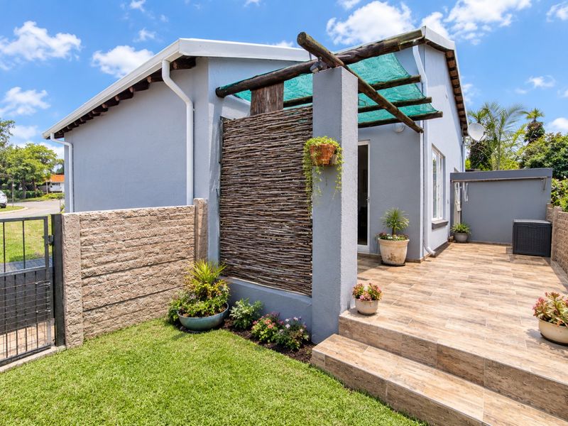 A well-maintained rear townhouse exterior featuring a tiled patio, timber pergola, and private garden area with secure boundary walling.