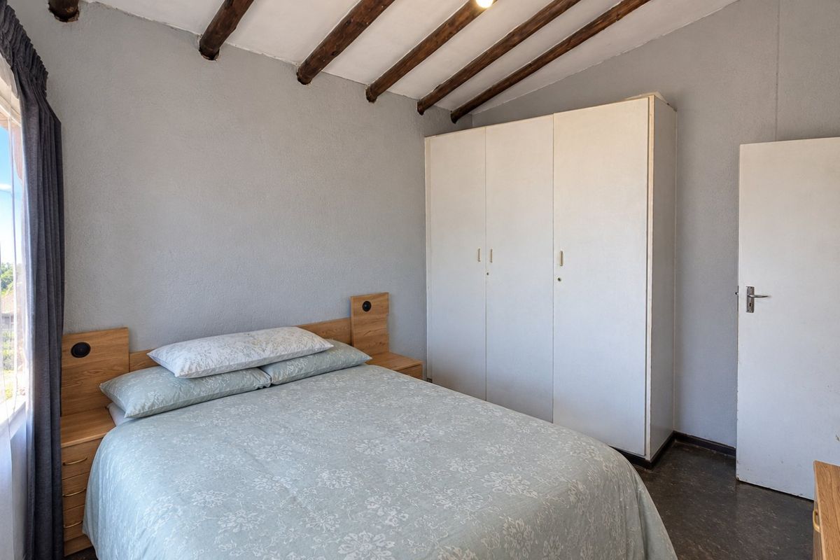 A bedroom featuring exposed timber ceiling beams, a built-in wardrobe, and tiled flooring.