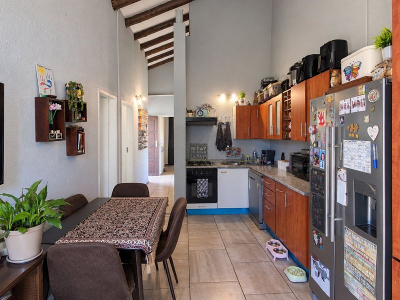 Open-plan kitchen and dining area featuring exposed timber ceiling beams, wooden cabinetry, and tiled flooring, creating a functional and connected living space.
