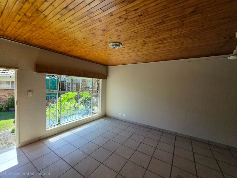 An empty living room featuring a warm timber tongue and groove ceiling, ceramic tiled flooring, and large windows with security bars.