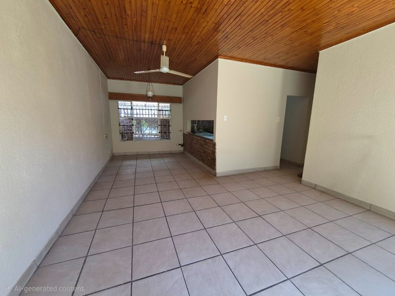 Spacious open-plan living area featuring a timber ceiling, ceiling fan, and ceramic tiled flooring with a built-in brick breakfast bar.