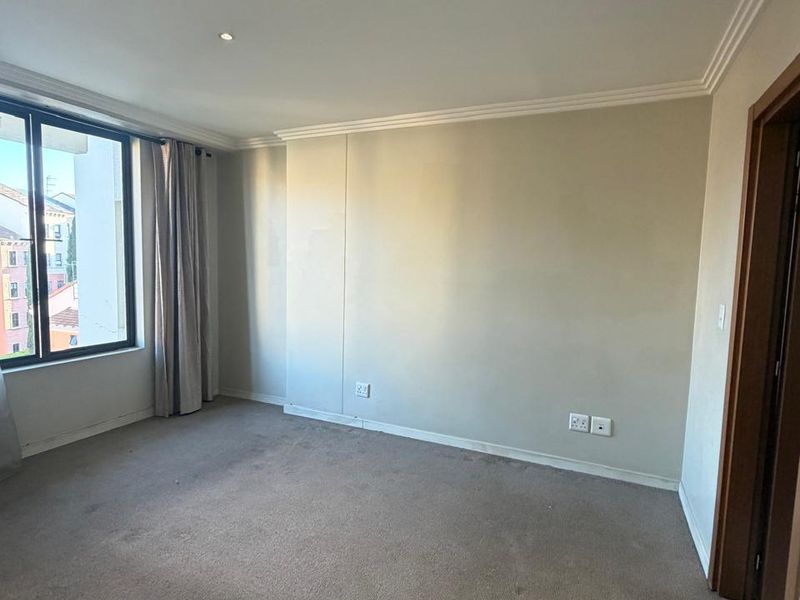 An empty bedroom featuring neutral walls, recessed downlighting, cornicing, and carpeted flooring, offering a blank canvas for personalization.