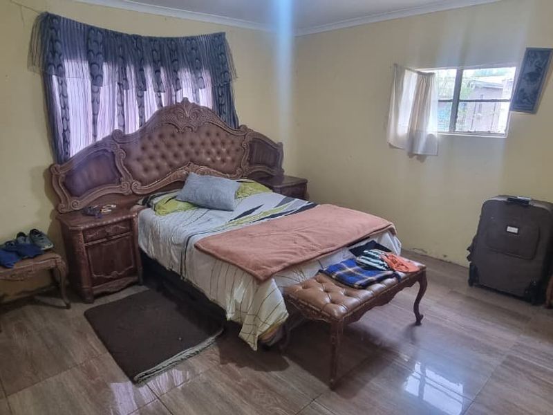 A bedroom featuring tiled flooring and windows, currently requiring cosmetic updates to the wall finishes to improve the overall aesthetic.
